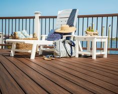 a white chair sitting on top of a wooden deck next to a bag and hat