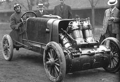 an old photo of men standing next to a car that is being driven by a machine