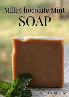 a bar of soap sitting on top of a wooden table next to a mint leaf