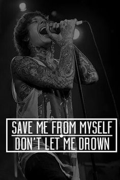 a man singing into a microphone with the words save me from myself don't