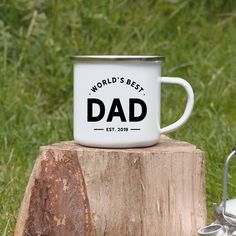 a white coffee mug sitting on top of a tree stump with the words world's best dad printed on it