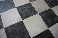 a black and white checkered floor with a toilet in the corner next to it