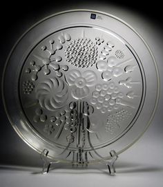 a decorative glass plate with intricate designs on the front and sides, set against a black background