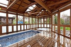 an indoor hot tub in the middle of a wood floored room with large windows