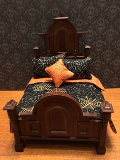 a wooden bed with black and gold bedspread on it's headboard