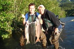 two men standing in the water holding fish