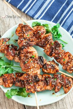 chicken skewers with sesame seeds and cilantro on a plate