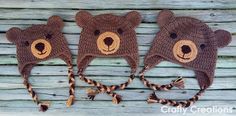 three crocheted hats with brown bears on them are hanging from a wooden wall