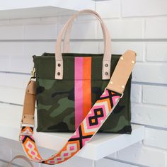 Small camo cotton canvas with pink and orange paint stripes. This smaller canvas tote will last a lifetime and is the perfect bag for weekends at the ranch or a trip to the city with the girls! Same natural leather used on totes as designers, Louis Vuitton and Jon Hart. This tote comes with patterned cross body strap that is pictured with bag. Details: Natural cotton coated canvas Painted 2 color stripes Veg-tan leather handles 2 interior side pockets 12.75"L x 9.75"H x 5"D *Custom bags take up Orange Canvas Travel Bag, Pink Canvas Bag With Leather Handles, Spring Travel Canvas Bag With Leather Handles, Pink Satchel Bag With Leather Trim, Pink Leather-trimmed Satchel Bag, Pink Canvas Tote Bag With Leather Handles, Orange Canvas Bag For Daily Use, Orange Canvas Tote Bag For Everyday Use, Spring Canvas Tote Bag With Leather Handles