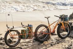 an orange bike parked on top of a sandy beach next to the ocean and waves