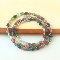 multicolored glass beaded bracelets on a wooden table next to a piece of wood