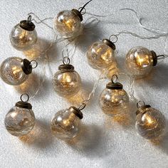 a bunch of glass balls with lights on them sitting on a white tableclothed surface