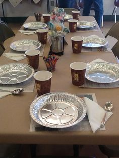 the table is set with silver plates, cups and utensils for an event