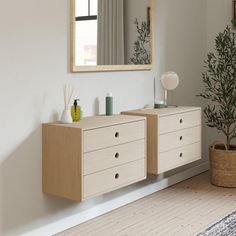 an empty room with a mirror, dresser and potted plant