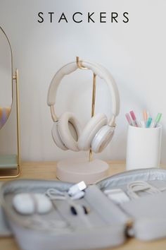 a desk with headphones and pens on it next to a pen holder, pencils and mirror