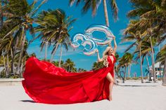 a woman in a red dress on the beach holding a large balloon with an omelet symbol