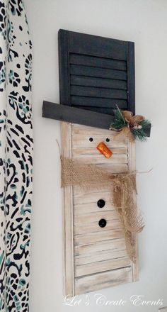 a snowman made out of an old shutter and some burlocks is hanging on the wall