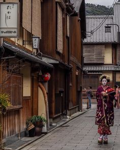 a woman in a geisha outfit walking down the street