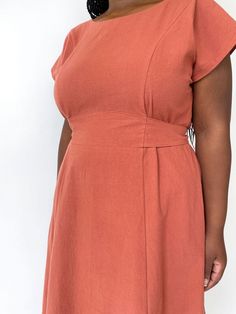 a woman in an orange dress poses for the camera with her hands on her hips