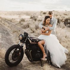 a man and woman sitting on a motorcycle in the middle of a desert road with dry grass