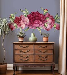 a painting of pink flowers on a dresser next to a potted plant