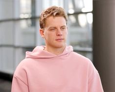 a young man in a pink hoodie looking off to the side