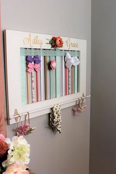 a wall hanging on the side of a room with flowers and ribbons attached to it