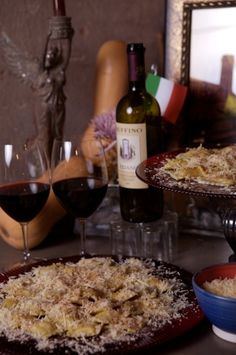 three plates with food and two glasses of wine on a table next to a statue