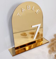 a teddy bear sitting next to a gold table number holder with the number seven on it