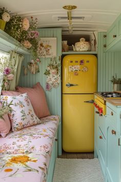 a yellow refrigerator sitting inside of a kitchen next to a couch and table with flowers on it