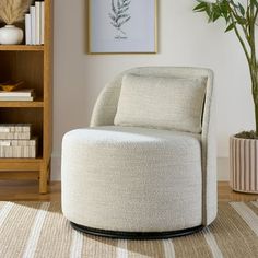 a white chair sitting on top of a wooden floor next to a book shelf filled with books