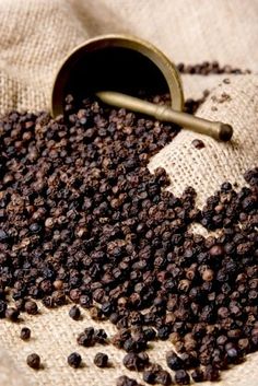 a pile of black pepper sitting on top of a table next to a measuring spoon