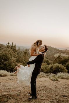 the bride and groom are posing for their wedding photo in front of some trees at sunset