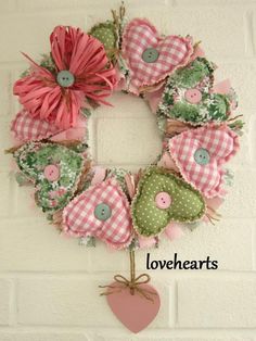 a pink and green wreath hanging on the side of a white brick wall with buttons