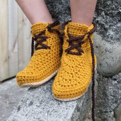 a close up of a person's feet wearing yellow crocheted shoes with brown laces