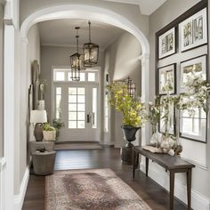 a hallway with pictures on the wall and a large rug in front of an entryway