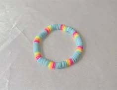 a bracelet with multicolored beads is on a white surface and looks like it has been made out of paper