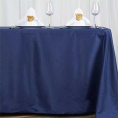 two wine glasses sitting on top of a blue table cloth with napkins in front of them