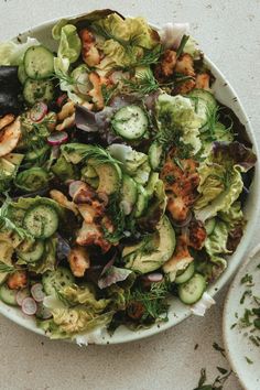 a salad with shrimp and cucumbers in a white bowl on top of a table