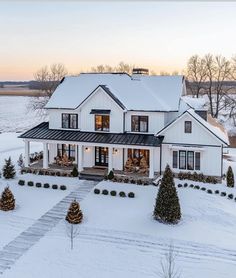 a large white house with lots of windows and trees in the front yard covered in snow