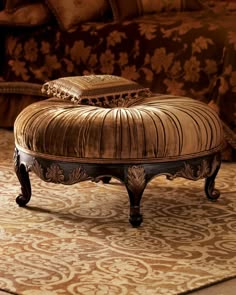 an ornate ottoman sits on top of a rug in front of a couch with pillows