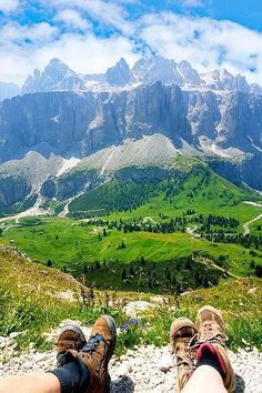 two people sitting on top of a mountain with their feet up in front of the camera