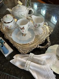 a tray with tea cups and saucers sitting on top of a marble countertop