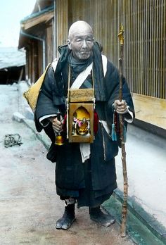 an old man is holding a stick and wearing a black outfit with gold trimmings