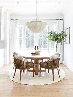 a dining room table with four chairs and a potted plant in the middle of it