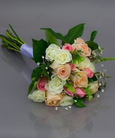 a bridal bouquet with roses and greenery on a gray surface, ready to be used as a bride's bouquet