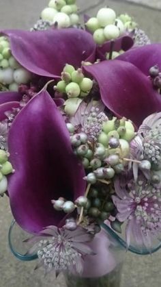 a vase filled with purple flowers on top of a cement floor next to a sidewalk