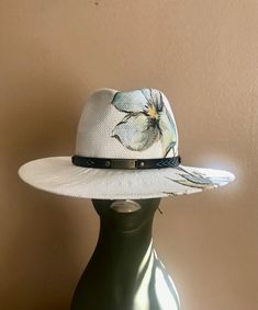 A white Toyo straw is hand-painted with water color and blocked into a fedora shape. Trimmed with western hat band . Head size is adjustable White Toquilla Straw Fedora With Short Brim, White Country Hat In Toquilla Straw, White Western Straw Hat With Short Brim, White Western Style Straw Hat With Short Brim, White Toquilla Straw Hat For Country Events, Artisan Fedora For Beach In Spring, White Short Brim Fedora In Toquilla Straw, White Country Style Hat In Toquilla Straw, White Western Fedora Panama Hat