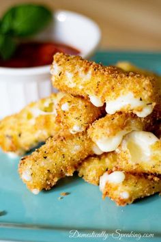 some fried food on a blue plate next to a bowl of sauce and toothpicks