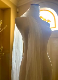 a mannequin with a veil draped over it's body in front of a window